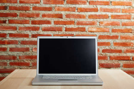 Laptop with blank screen on the desk and red brick wall work from home or study onlineの写真素材