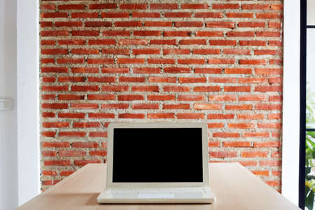 Laptop with blank screen on the desk and red brick wall work from home or study onlineの写真素材