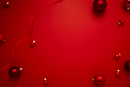Blurred Red Christmas baubles decoration on paper red background with copy space for New Year and...