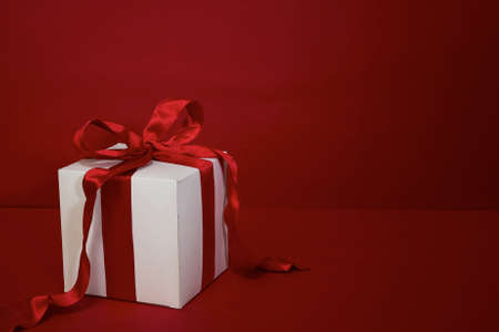 Gift box Christmas with red ribbon on red backgroundの写真素材