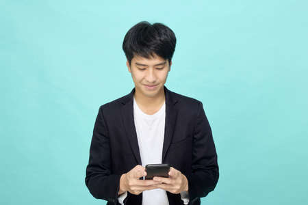 Handsome young Asian Businessman texting Work, holding smartphone, stay connected using mobile phone, internet, scroll social network online,の写真素材
