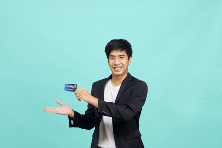 Portrait of young businessman Holding and showing credit card on hand on Isolated blue backgroundの写真素材