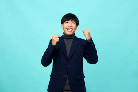 young Southeast Asian man with happy and self-confident positive expression with crossed arms in light blue studio isolated backgroundの写真素材