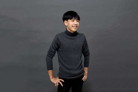 Young handsome Asian man posing to copy space on gray isolated backgroundの写真素材