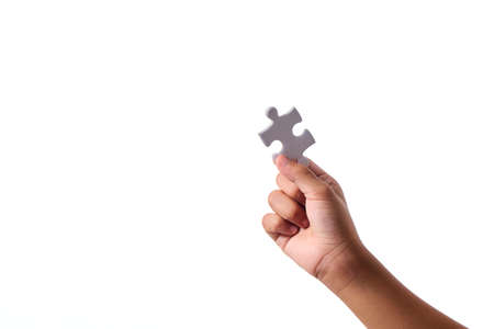 Hand holding a blank jigsaw piece on a white background  copy space for textの写真素材