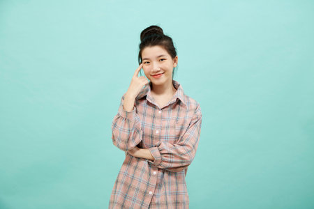 Cheerful cute Asian woman thinking on bright blue color backgroundの写真素材