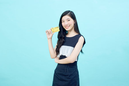 Portrait beautiful young Asian woman smile with the credit card bright blue color backgroundの写真素材