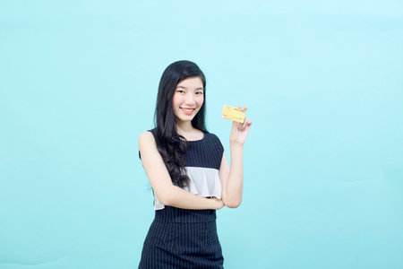 Portrait beautiful young Asian woman smile with the credit card bright blue color backgroundの写真素材