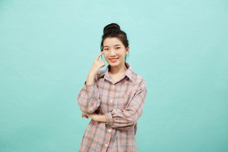 Cheerful cute Asian woman thinking on bright blue color backgroundの写真素材
