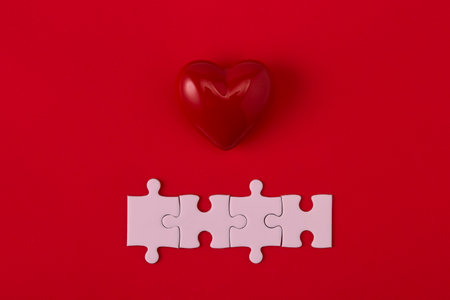 Top view heart-shaped symbol and jigsaw pieces on red background textured for banner designの写真素材