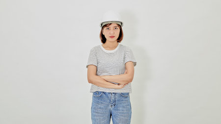 Smiling Asian businesswoman in a safety helmet and suit cross arms and selling new buildings construction manager on white backgroundの写真素材