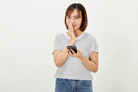 Smiling Asian woman using a smartphone, standing against texting on a mobile phone on white background, people and technology conceptの写真素材
