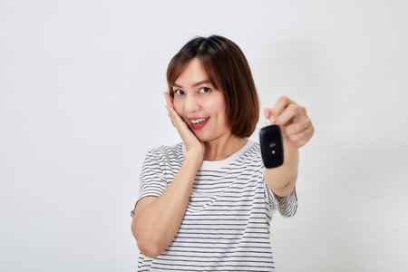 Beautiful young business Asian woman with brunette short hair wearing a t-shirt and jeans with a car...