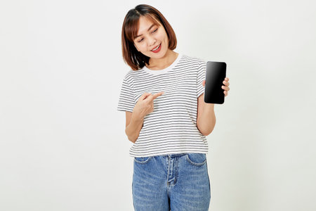 Satisfied smiling asian young woman recommending mobile phone app, website company on a smartphone, showing screen on white background.の写真素材