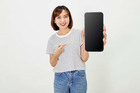 Satisfied smiling asian young woman recommending mobile phone app, website company on a smartphone, showing screen on white background.の写真素材