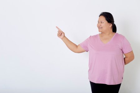 Beautiful Asian plus-size woman smiles with positive emotion, feeling happy and proud of her body overweight. Portrait shot on white background with copy space.の写真素材