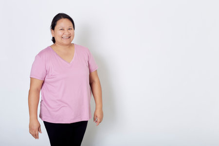 Beautiful Asian plus-size woman smiles with positive emotion, feeling happy and proud of her body overweight. Portrait shot on white background with copy space.の写真素材