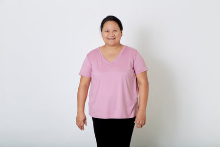 Beautiful Asian plus-size woman smiles with positive emotion, feeling happy and proud of her body overweight. Portrait shot on white background with copy space.の写真素材
