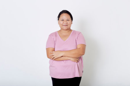 Beautiful Asian plus-size woman smiles with positive emotion, feeling happy and proud of her body overweight. Portrait shot on white background with copy space.の写真素材