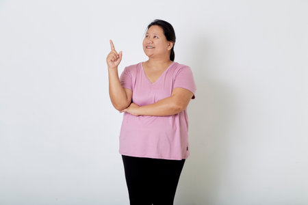 Beautiful Asian plus-size woman smiles with positive emotion, feeling happy and proud of her body overweight. Portrait shot on white background with copy space.の写真素材