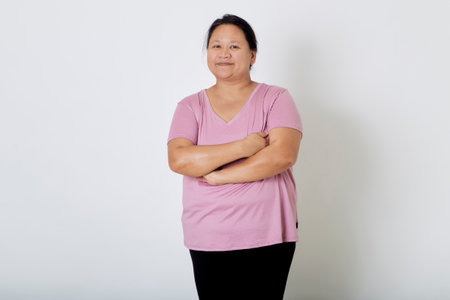 Beautiful Asian plus-size woman smiles with positive emotion, feeling happy and proud of her body overweight. Portrait shot on white background with copy space.の写真素材