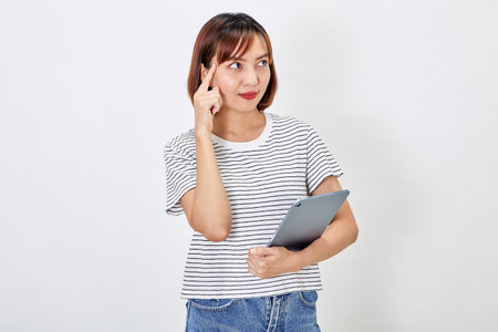 Portrait of a smiling beautiful Asian woman freelancer using a digital tablet and looking pleased with the device screen, shopping online, on white backgroundの写真素材
