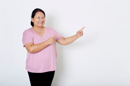 Beautiful Asian plus-size woman smiles with positive emotion, feeling happy and proud of her body overweight. Portrait shot on white background with copy space.の写真素材