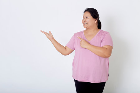 Beautiful Asian plus-size woman smiles with positive emotion, feeling happy and proud of her body overweight. Portrait shot on white background with copy space.の写真素材
