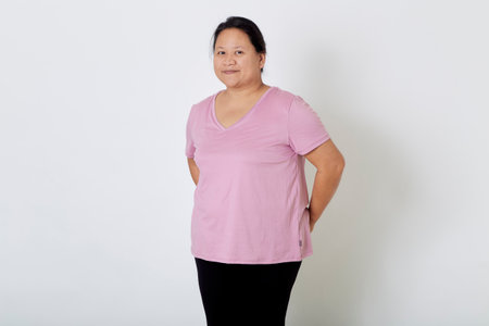 Beautiful Asian plus-size woman smiles with positive emotion, feeling happy and proud of her body overweight. Portrait shot on white background with copy space.の写真素材