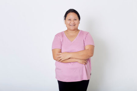 Beautiful Asian plus-size woman smiles with positive emotion, feeling happy and proud of her body overweight. Portrait shot on white background with copy space.の写真素材