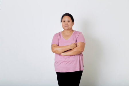 Beautiful Asian plus-size woman smiles with positive emotion, feeling happy and proud of her body overweight. Portrait shot on white background with copy space.の写真素材