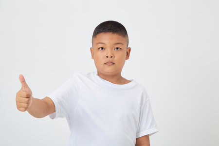 Cute smiling Asian boy in a plain white t-shirt looking at the camera in an isolated studio light white color backgroundの写真素材