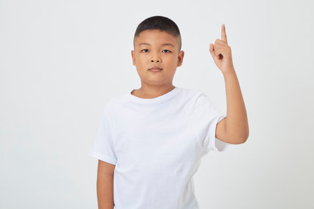 Cute smiling Asian boy in a plain white t-shirt looking at the camera in an isolated studio light white color backgroundの写真素材
