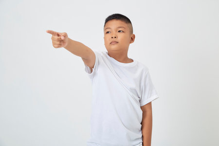 Cute smiling Asian boy in a plain white t-shirt looking at the camera in an isolated studio light white color backgroundの写真素材