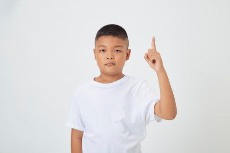 Cute smiling Asian boy in a plain white t-shirt looking at the camera in an isolated studio light white color backgroundの写真素材