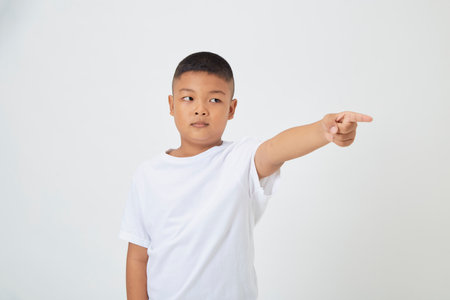 Cute smiling Asian boy in a plain white t-shirt looking at the camera in an isolated studio light white color backgroundの写真素材
