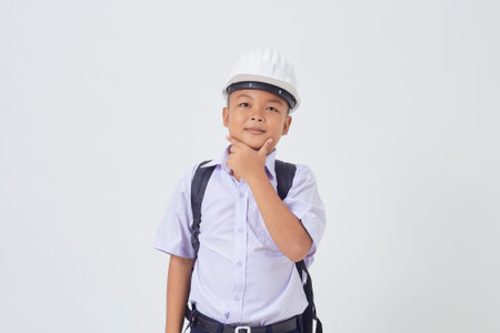 A young Asian cute boy standing in a Thai school uniform with a backpack bag and safety helmet  on a white background banner. Back to schoolの写真素材