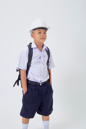 A young Asian cute boy standing in a Thai school uniform with a backpack bag and safety helmet  on a white background banner. Back to schoolの写真素材