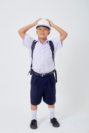 A young Asian cute boy standing in a Thai school uniform with a backpack bag and safety helmet  on a white background banner. Back to schoolの写真素材