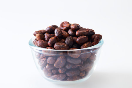 Close up Roasted cocoa beans in a glass bowl on white backgroundの写真素材