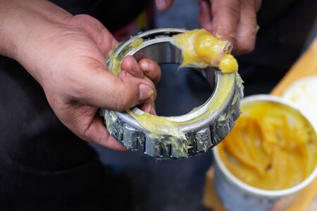 An Asia man putting lithium grease EP (extreme pressure) NLGI 3 into wheel bearing for ten wheel track by hand in the garage. Industrial and automotive conceptの写真素材