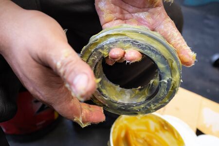 An Asia man putting lithium grease EP (extreme pressure) NLGI 3 into wheel bearing for ten wheel track by hand in the garage. Industrial and automotive conceptの写真素材