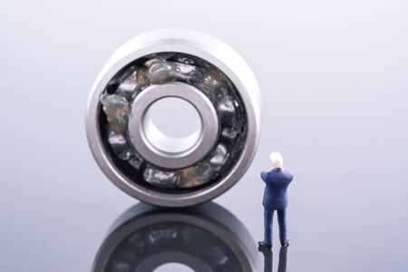 Miniature people : Business man wear blue suit standing in front of ball bearing. Ball bearing place on the other ball bearing. Industrial and business conceptの写真素材