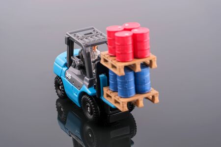 Miniature People : Engineer driving forklift and lift up palette which have four red drums and four...