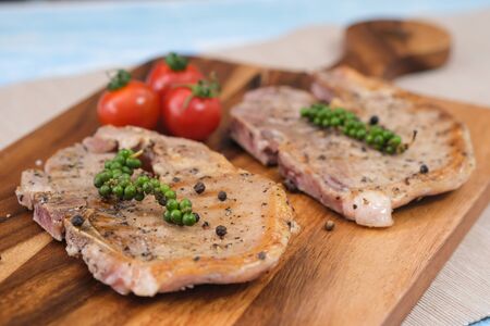 Homemade cooking grill of pork steak with fresh preper and tomato put on the wooden plate. Food and...