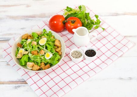 Fresh vegetable salad with fresh tomato, cucumber, lettuce, spinach, egg on plate topping with biscuits. There is a dressing in the small cup. Healty food conceptの写真素材