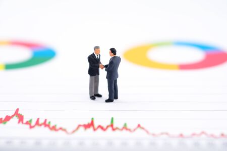 Miniature people:Businessman standing and shake hand with team with copy space. Financial crisis. Data analysis. Stock market volatility risk. Information for investment.の写真素材