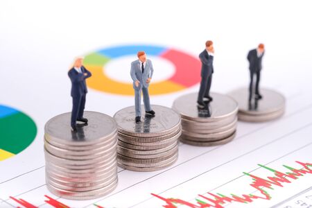 Miniature people:Businessman teams standing on coin with copy space. Financial crisis. Data analysis. Stock market volatility risk. Information for investment. Focus on second people.の写真素材