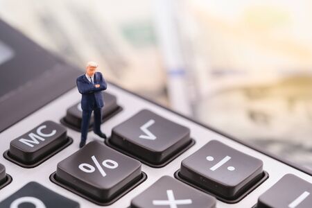 Miniature people:Businessman standing on calculator with copy space. Financial crisis. Data analysis. Stock market volatility risk. Information for investment. Financial conceptの写真素材