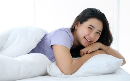 Young beautiful Asia woman wake up and smile. Enjoy on the soft bed at the modern bedroom and...
